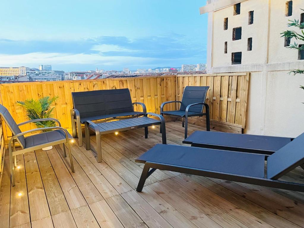 eine Terrasse mit Stühlen und Tischen auf einer Holzterrasse in der Unterkunft Honoré - Rooftop- Centre Vieux Port in Marseille