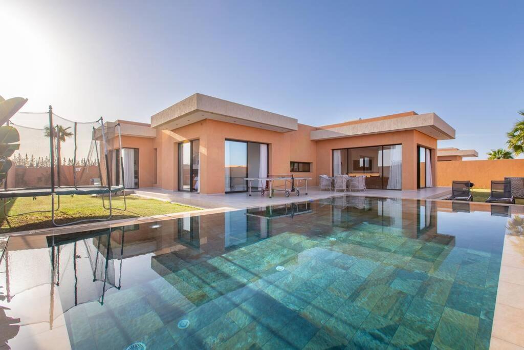 une villa avec une piscine en face d'une maison dans l'établissement Villa Menara, personnels inclus, à Marrakech