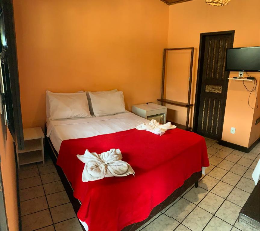 um quarto com uma cama com um cobertor vermelho em Pousada Três Corações em Arraial d'Ajuda
