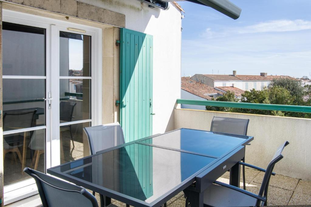 een glazen tafel en stoelen op het balkon van een huis bij Appartement duplex "Atlantis" proche du port in Saint-Martin-de-Ré