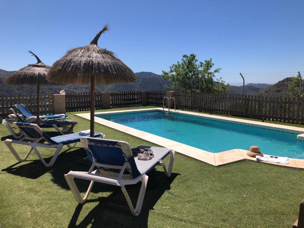 una piscina con dos sillas y una sombrilla en Mirador Del Burro, en Casabermeja