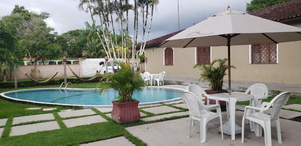 una mesa con sillas y una sombrilla junto a la piscina en CASA OURO VERDE - Praia de Mosqueiro, en Belém