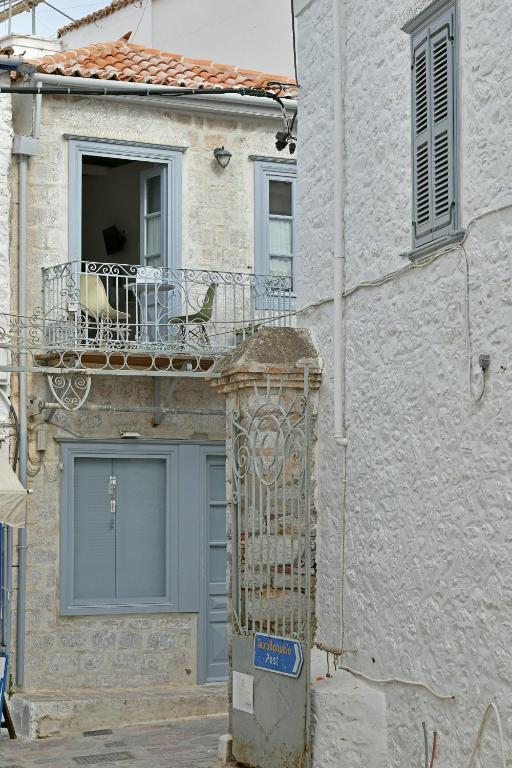 a building with a balcony and a gate in front of it at Centrál in Hydra