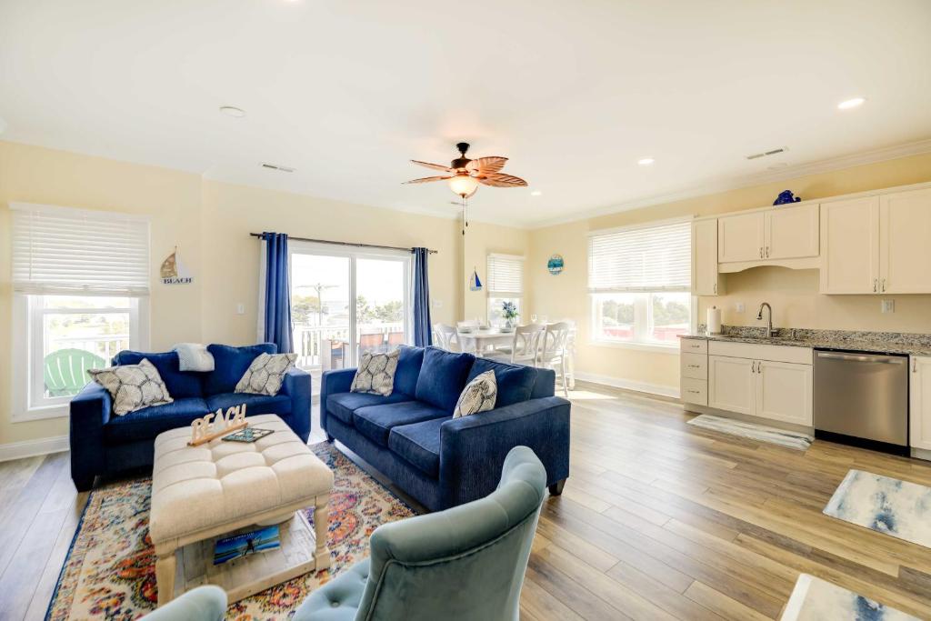 a living room with blue couches and a kitchen at Emerald Isle Vacation Home Walk to Beach! in Emerald Isle
