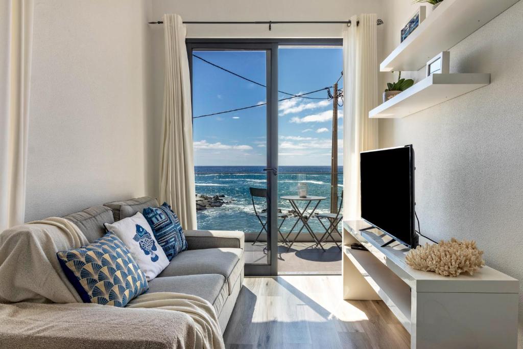 a living room with a couch and a view of the ocean at Casa Homem do Mar in Paul do Mar