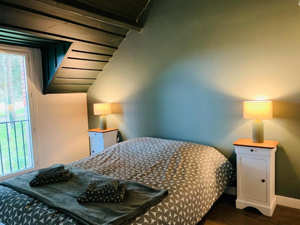 een slaapkamer met een bed, 2 lampen en een raam bij Cottage in Missillac