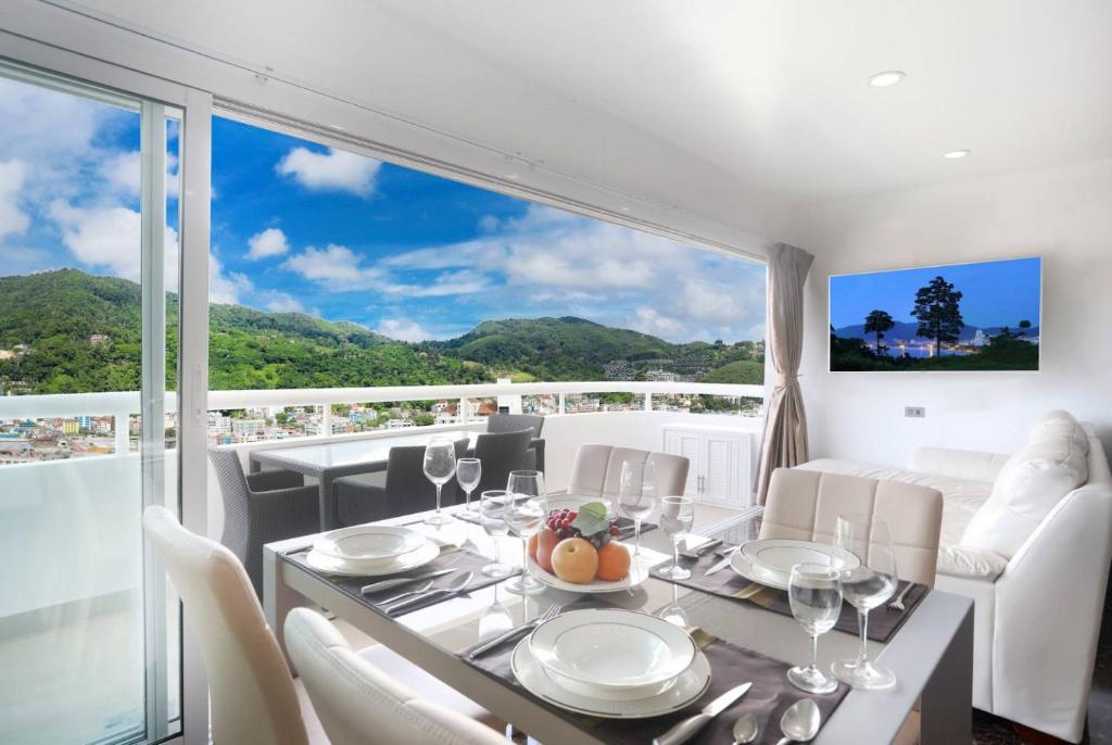 a dining room with a table and chairs and a large window at PATONG TOWER FAMILY WELCOME by PTA in Patong Beach