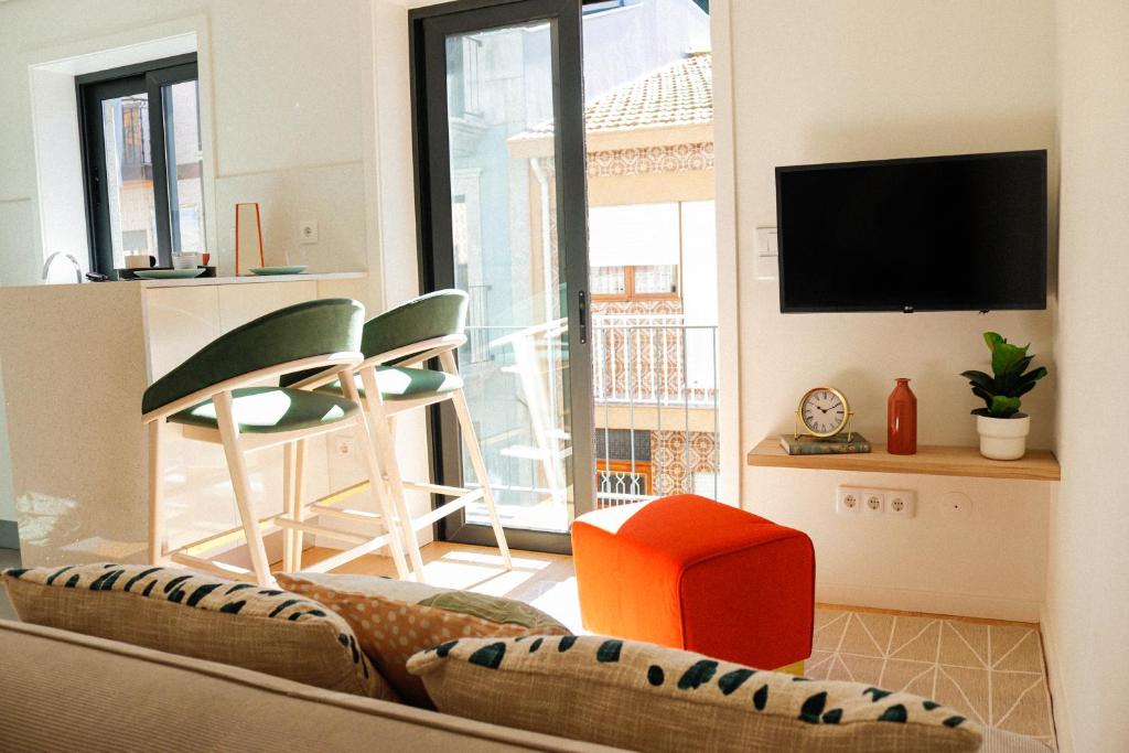 - un salon avec une télévision, un canapé et des chaises dans l'établissement Fish Village Deluxe, à Vila Nova de Gaia