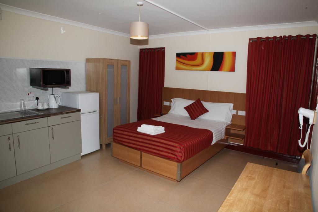 Un pequeño dormitorio con una cama y una cocina. en Grove Apartments, en Londres