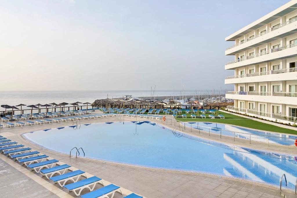 a large swimming pool next to a hotel and the ocean at Alua Atlantico Golf - All Inclusive in San Miguel de Abona