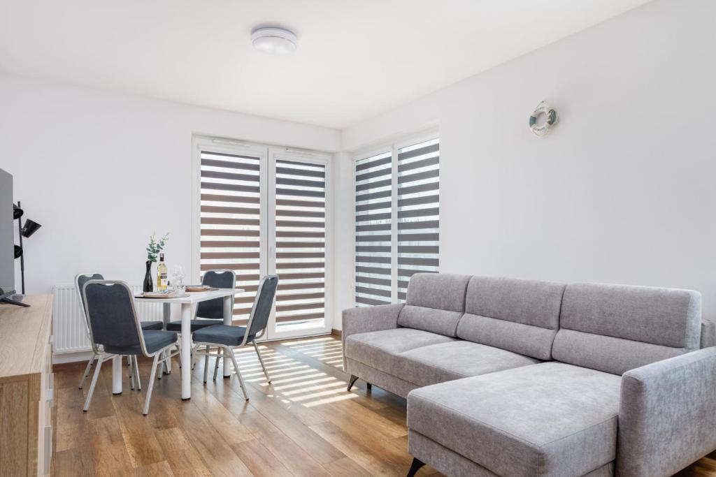 a living room with a couch and a table and chairs at Coast Breeze Apartment by Renters in Kołobrzeg