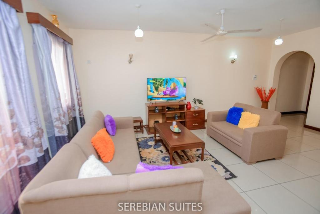 a living room with two couches and a tv at Serebian Suites in Mombasa