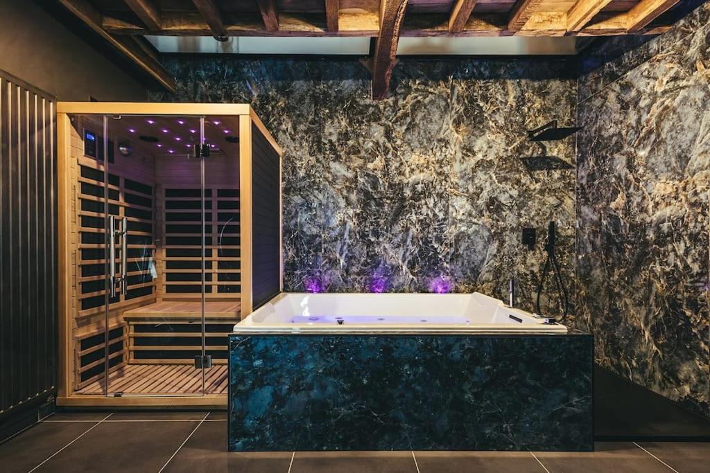 a bath tub in a room with a stone wall at Le Duplex de l'Etoile home cinéma jacuzzi et sauna privatif in Longmesnil