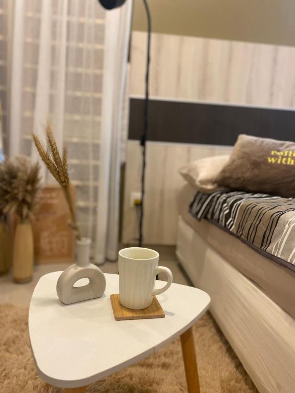 a table with a coffee cup on it next to a bed at The Sugar'Barn Studio D Perdana kota bharu in Kota Bharu