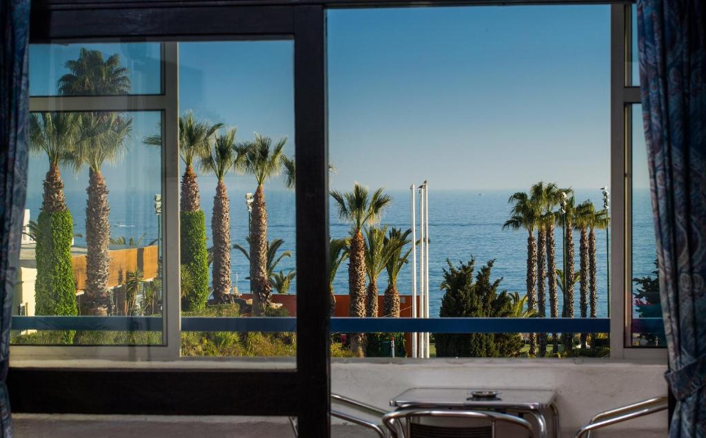 a room with a view of the ocean and palm trees at Apartamentos Azul Mar in Albufeira