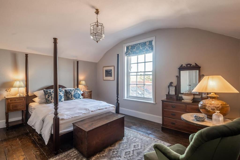 a bedroom with a canopy bed and a living room at Sarah's - A townhouse apartment in Georgian Holt in Holt