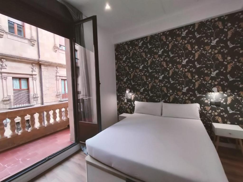 1 dormitorio con cama blanca y ventana en Apartamentos Margarita by gaiarooms, en Salamanca