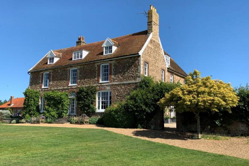 a large brick house with a lawn in front of it at Butley Priory Farmhouse in Woodbridge