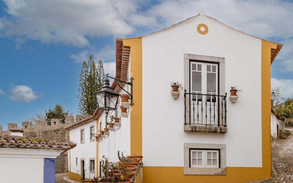 Casa de S. Thiago de Obidos في أوبيدوس: منزل ابيض واصفر مع بلكونه