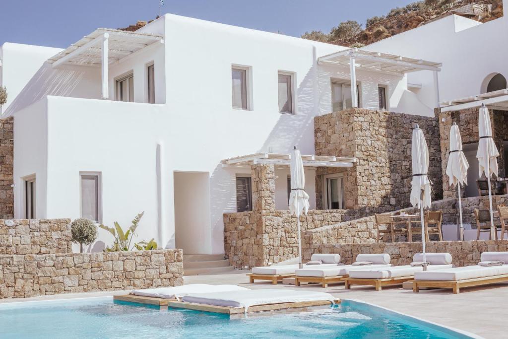 a pool with chairs and umbrellas next to a building at Arocaria Mykonos in Mýkonos City