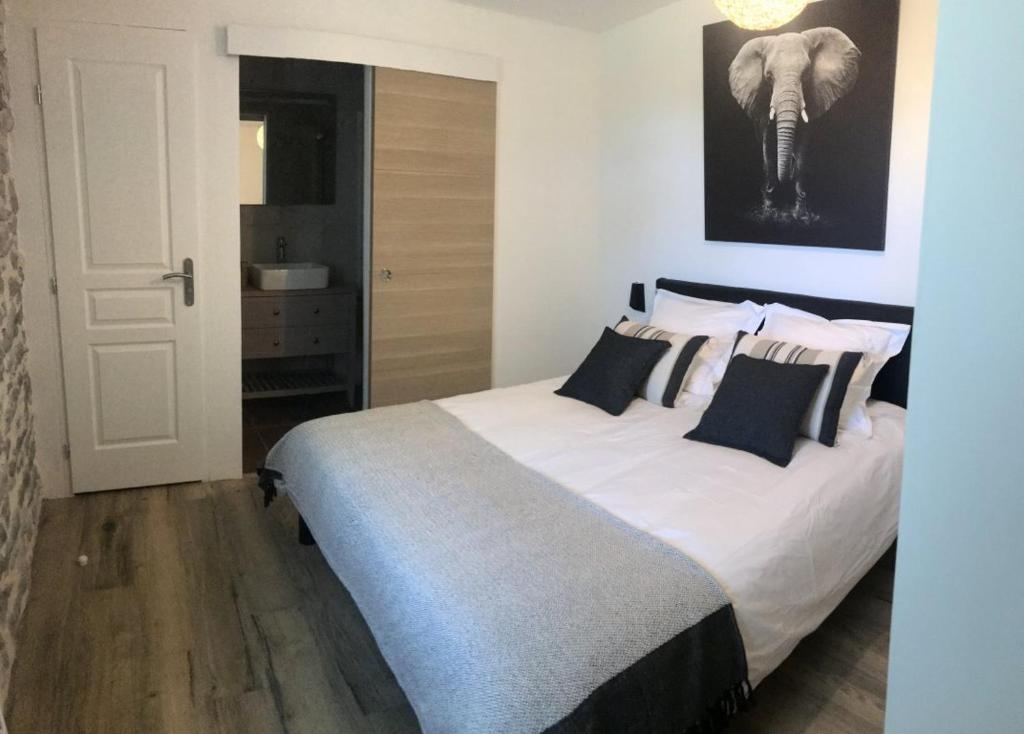 una camera da letto con un grande letto con cuscini bianchi e neri di le Clos Lotois - Chambre d'hôtes de charme entre Padirac et Rocamadour a Gramat