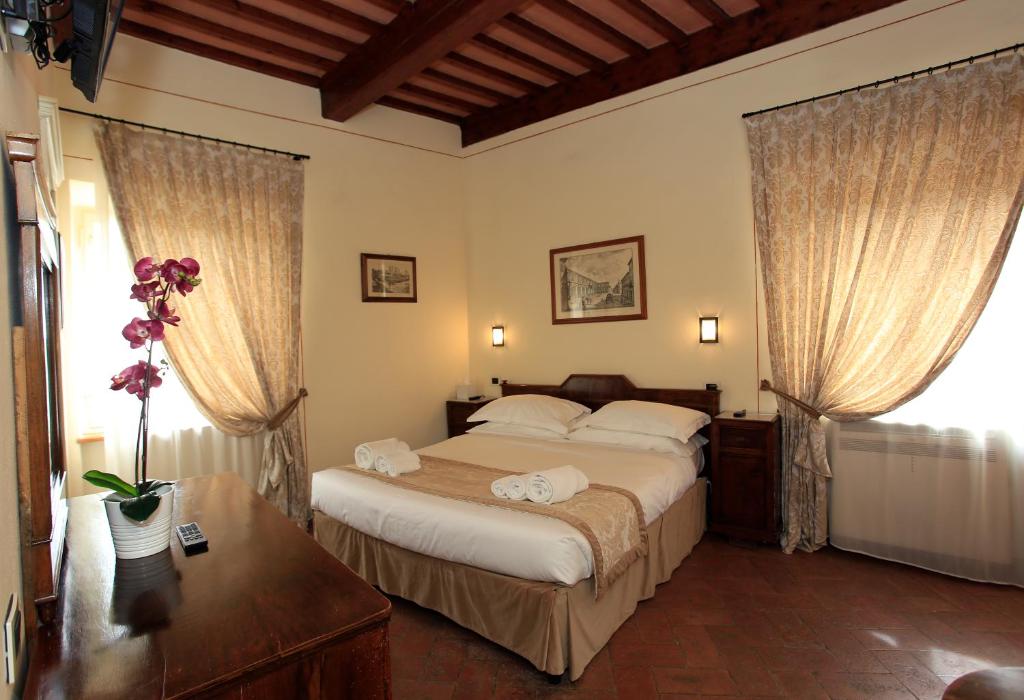 una camera con un grande letto e due finestre di Palazzo Mari a San Gimignano