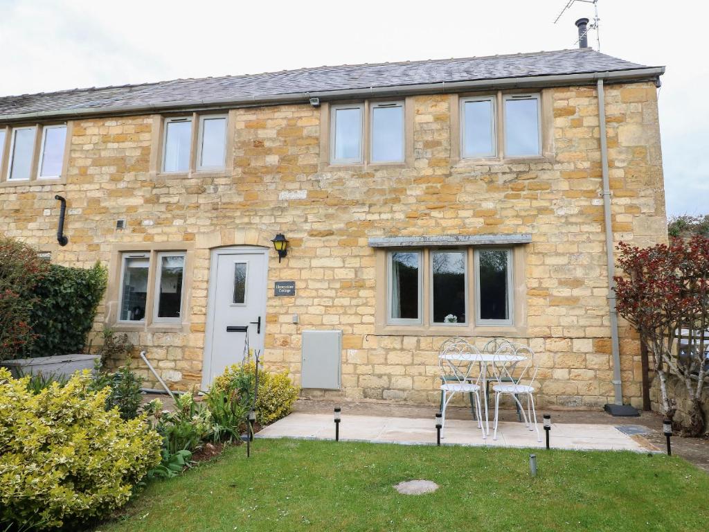 a stone house with a table and chairs in a yard at Honeystone Cottage in Moreton in Marsh