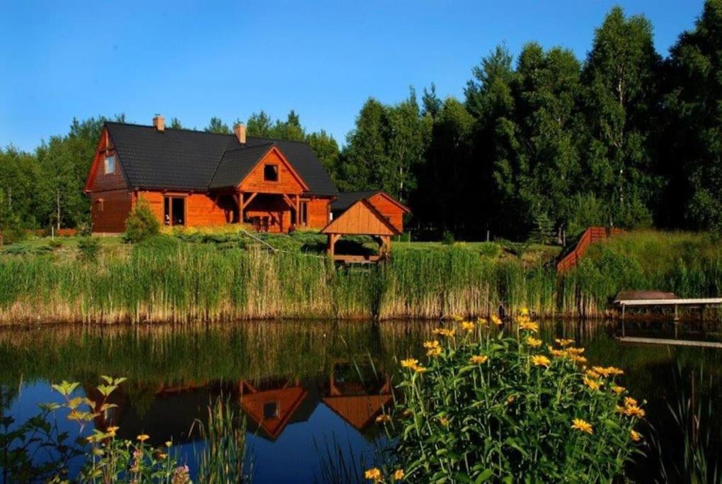 een rode schuur wordt weerspiegeld in het water van een meer bij Uroczy drewniany dom w ciszy i spokoju in Redułty