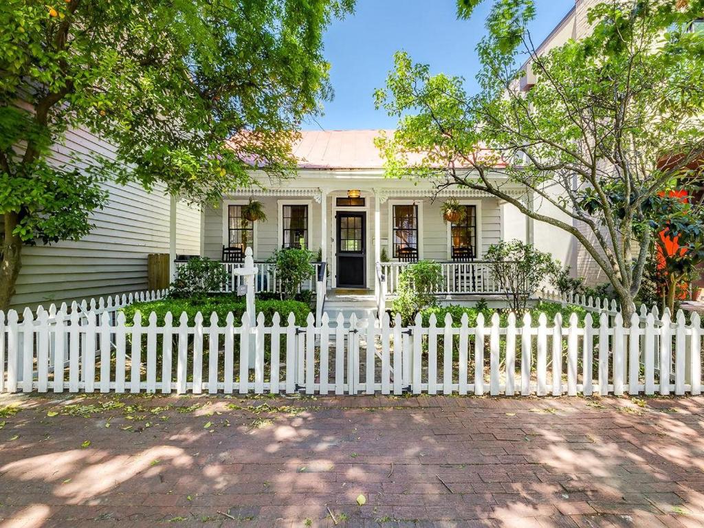 a white picket fence in front of a white house at Waldburg Cottage in Savannah