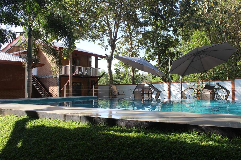 einen Pool mit Stühlen und Sonnenschirmen im Wasser in der Unterkunft Tepraas Sigiriya in Sigiriya