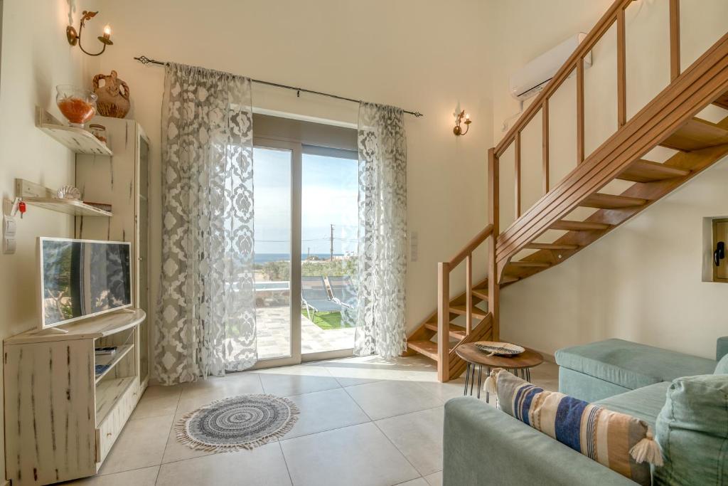 sala de estar con sofá azul y puerta corredera de cristal en Pink Sand Villas en Agios Padeleimon