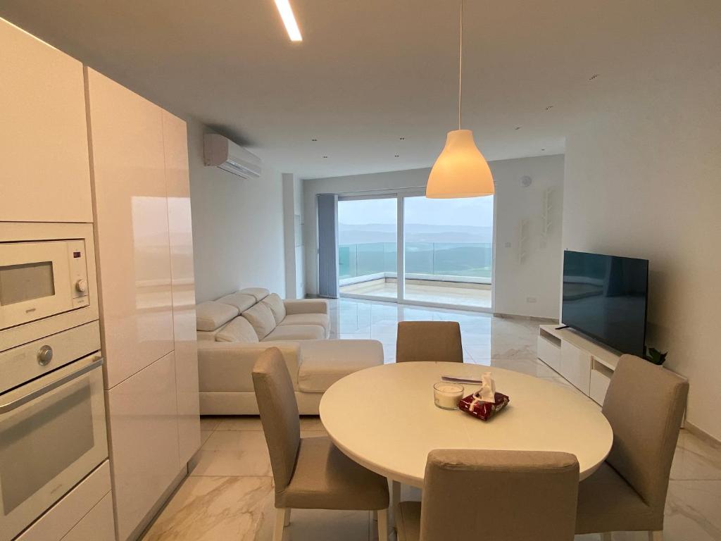een keuken en een woonkamer met een tafel en een bank bij A52 - Apartment with Sea and Country Views in Mellieħa
