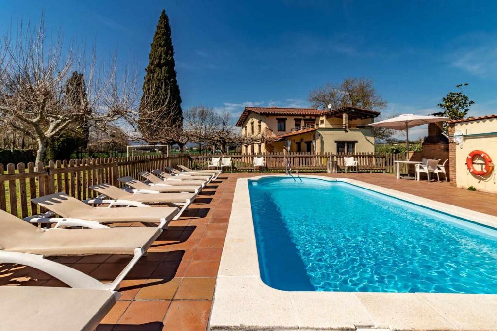 a swimming pool with lounge chairs and a house at Can Salvà Casa rural en magnífico entorno natural in Girona