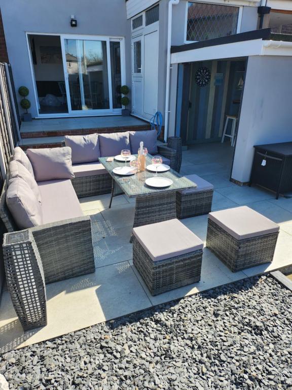 a patio with a couch and a table and chairs at Delightful newly renovated 3-bed house with garden beach hut in Blackpool