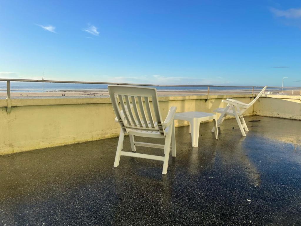 dwa białe krzesła siedzące na balkonie z widokiem na ocean w obiekcie Berck w mieście Berck-sur-Mer