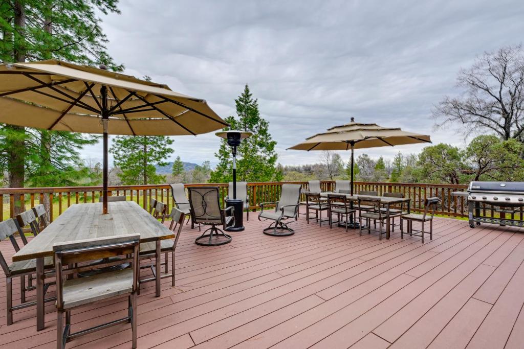 a wooden deck with tables and chairs and umbrellas at Mudge Ranch Retreat near Bass Lake with EV Charger in Coarsegold