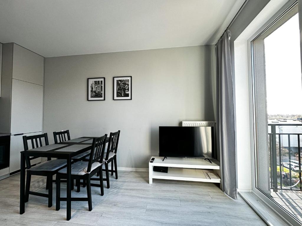 uma sala de jantar com uma mesa e cadeiras e uma televisão em Apartament Szczecin em Szczecin