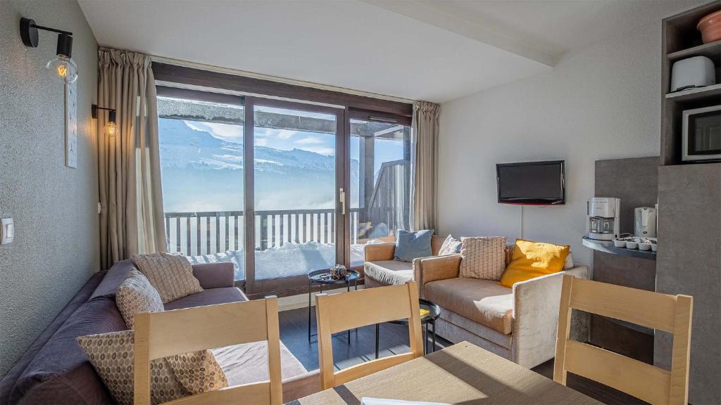 een woonkamer met een bank en een tafel bij Madame Vacances Les Terrasses De Véret in Flaine