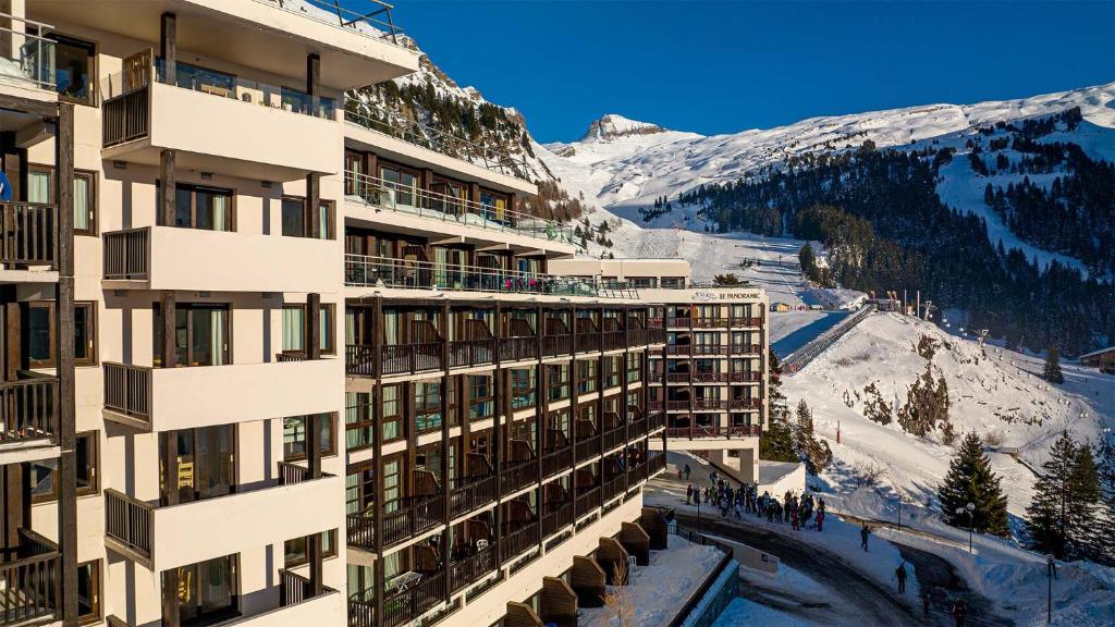 a building with a snow covered mountain in the background at Madame Vacances Les Terrasses De Véret in Flaine