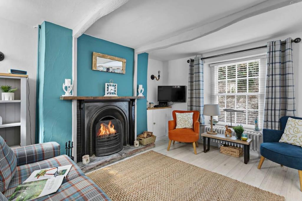 a living room with a fireplace and a blue wall at Family Tides Brixham in Brixham