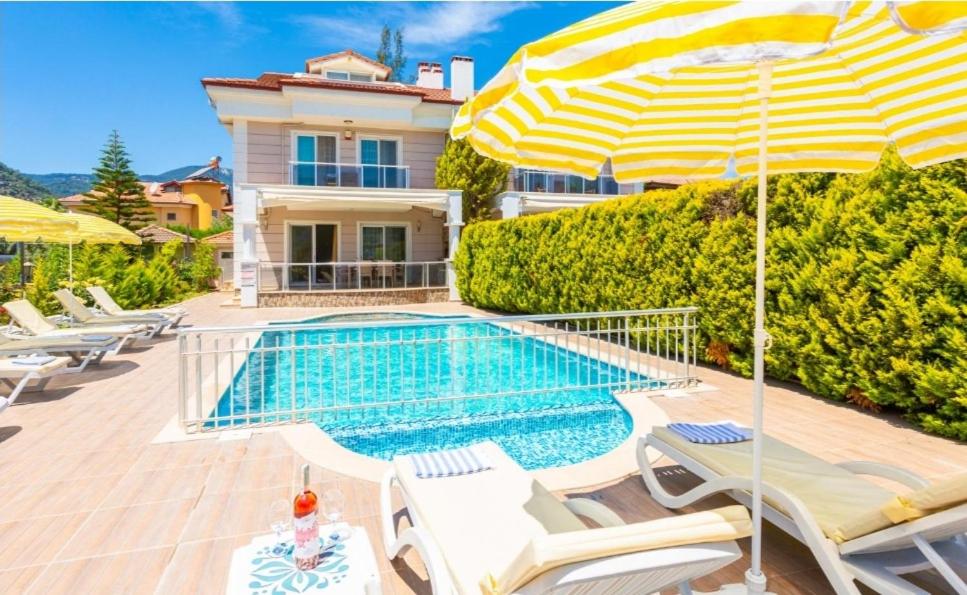 a villa with a swimming pool with chairs and an umbrella at Villa Canberk in Dalyan