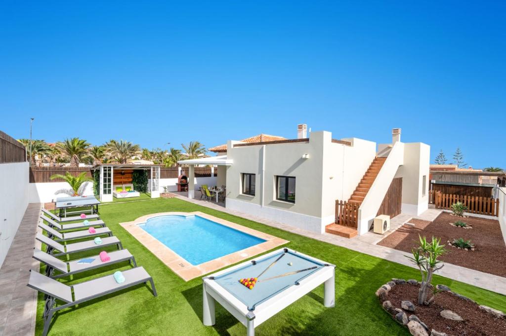 a backyard with a swimming pool and a house at Villa Caleta Del Sol by Villa Plus in Caleta De Fuste