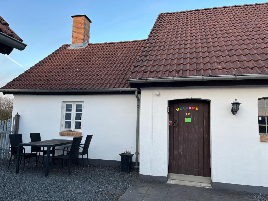a white house with a wooden door and a table at Auszeit im Grünen in Fårvang