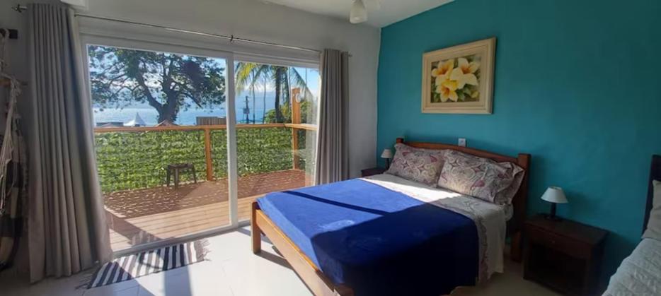 a bedroom with a bed and a large window at RETIRO DA VILA , você no coração de Ilhabela in Ilhabela