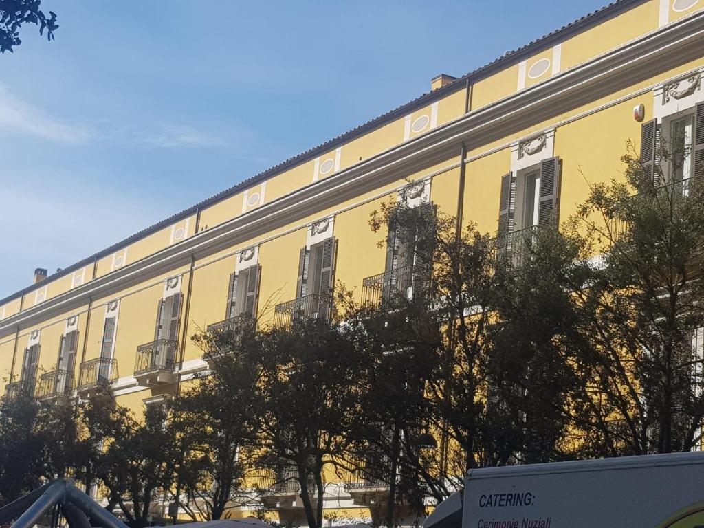 um edifício amarelo com árvores em frente em La Mansarda di Corso Umberto em Pescara