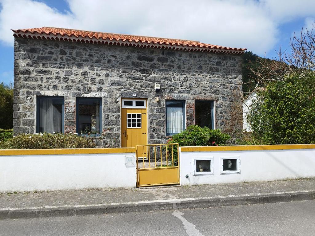 a stone house with a yellow door on a street at Casa dos Platanos-Family Home in Sete Cidades