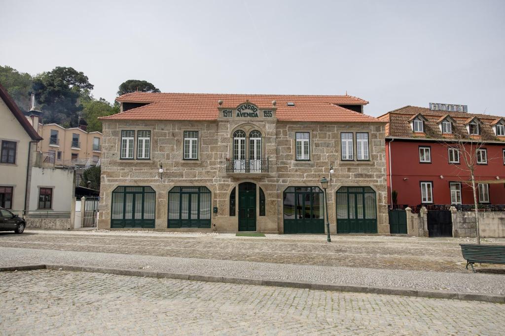 un gran edificio de piedra con un banco delante en DOURO B&B Avenida, en Resende