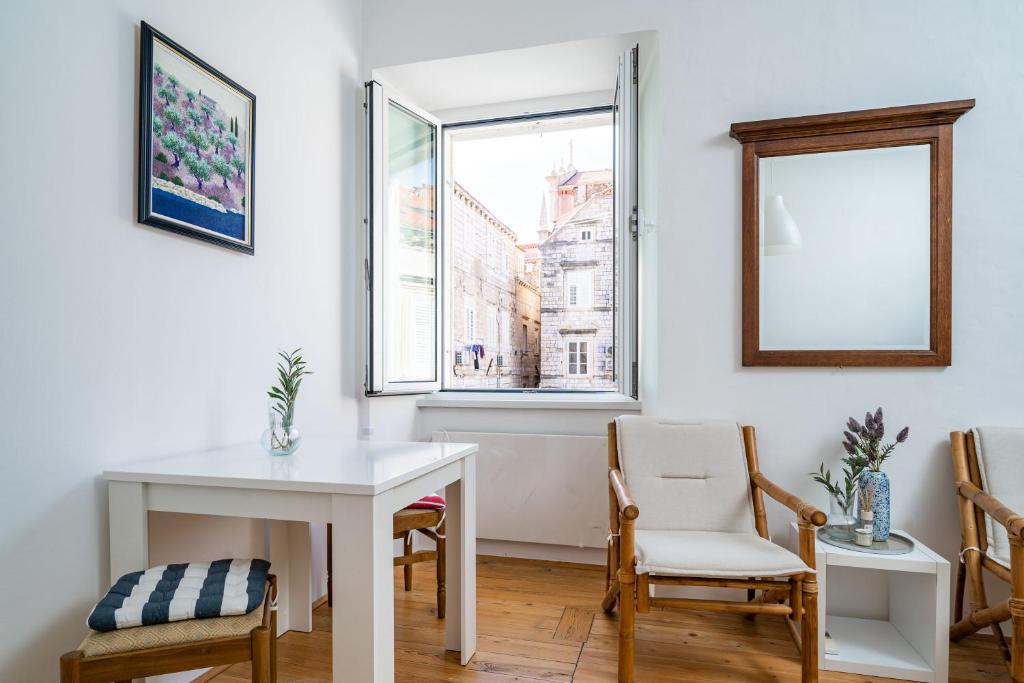 a white table and chairs in a room with a window at LAUS II, Lovely Apartment in Old town Dubrovnik in Dubrovnik