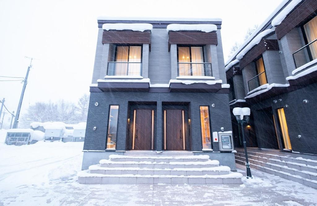 uma casa com neve nos degraus em frente em Ｑｕｅｅｎｓ Ｐａｒｋ ＣＫ ＶＩＬＬＡＧＥ Ｎｉｓｅｋｏ Ｈｉｒａｆｕ Ｉ - Vacation STAY 14145 em Niseko