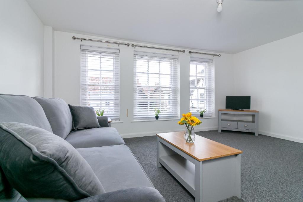 a living room with a couch and a table with flowers at The Oldtown Lodge in Stevenage